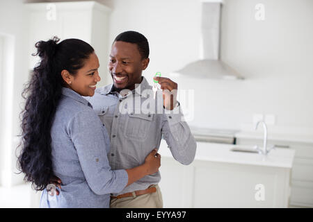 Couple hugging and holding keys in new home Stock Photo