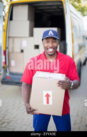 Black delivery man holding package Stock Photo