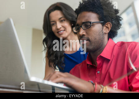 Hispanic business people using laptop at glass office desk Stock Photo