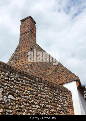 Vernacular brick construction of house with gable end showing complex herringbone design and flint cobbled wall Stock Photo