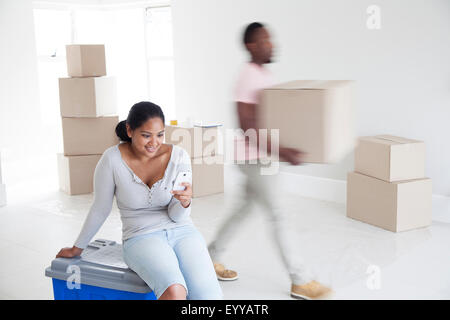 Woman relaxing with man carrying boxes in new home