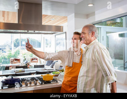 Caucasian father and son taking selfie in kitchen Stock Photo