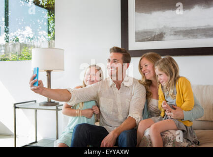 Caucasian family taking selfie on sofa Stock Photo