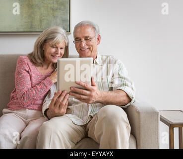 Older Caucasian couple using digital tablet on sofa Stock Photo
