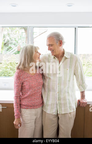 Older Caucasian couple hugging in kitchen Stock Photo