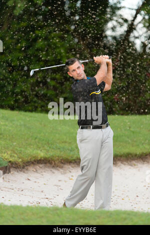 Caucasian man chipping from golf course sand trap Stock Photo