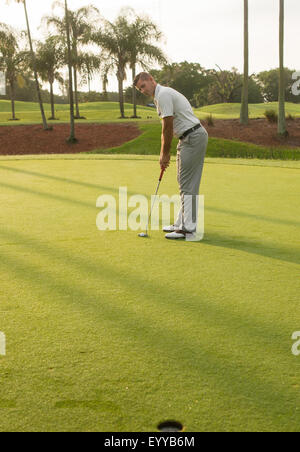 Caucasian man putting on golf course Stock Photo