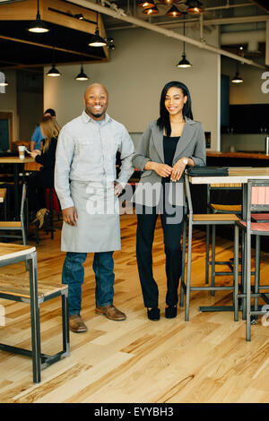 Waiter and businesswoman smiling in cafe Stock Photo