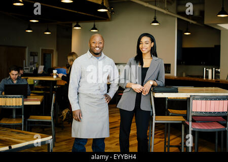 Waiter and businesswoman smiling in cafe Stock Photo