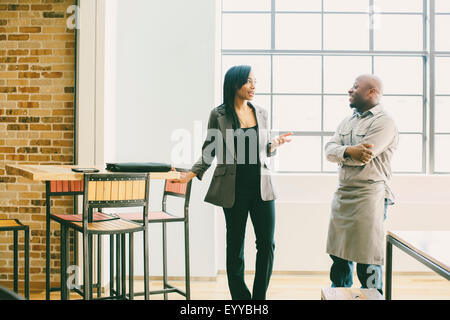 Black businesswoman and waiter talking in cafe Stock Photo