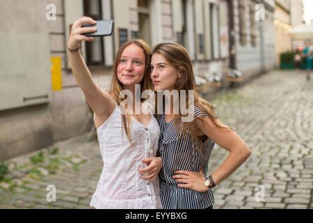 Selfie. Teenage girls take pictures of themselves on the smartphone on the street. Stock Photo
