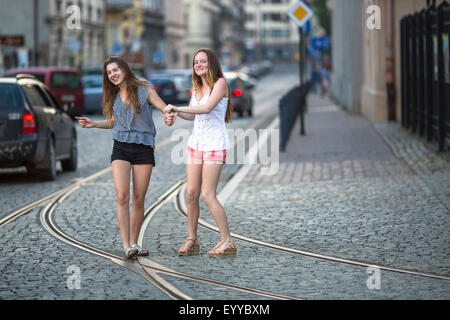 Funny teenage girls together walking on the pavement on the street. Stock Photo