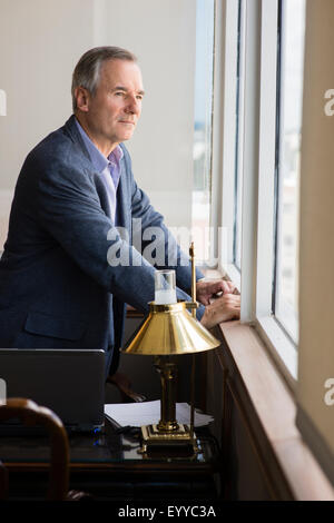 Caucasian businessman looking out office window Stock Photo