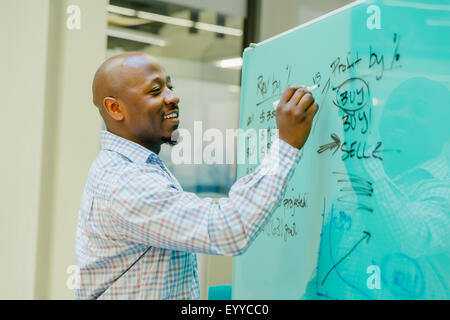 Black businessman writing on whiteboard Stock Photo