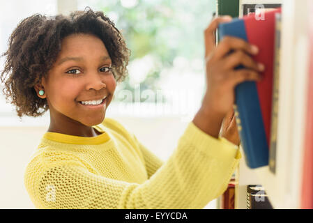 Black student choosing book from library shelf Stock Photo