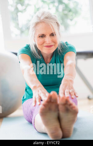 Older Caucasian woman stretching in gym Stock Photo