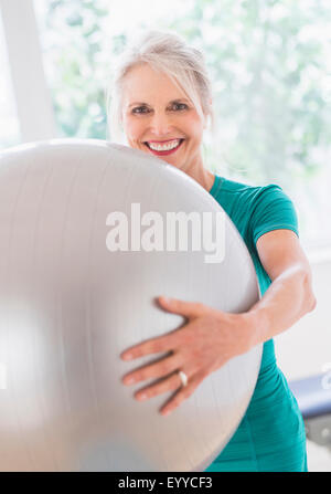 Older Caucasian woman holding exercise ball in gym Stock Photo