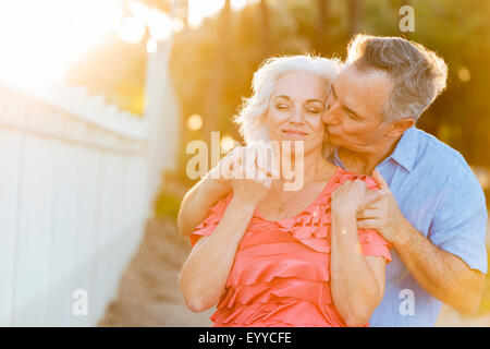 Older Caucasian couple kissing on beach Stock Photo