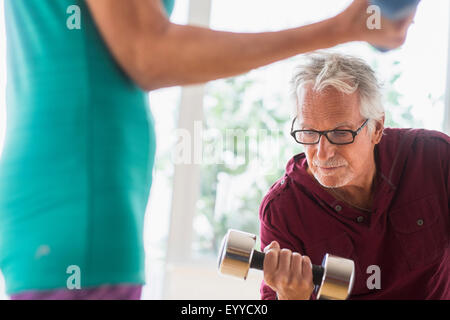 Older Caucasian couple lifting weights in gym Stock Photo