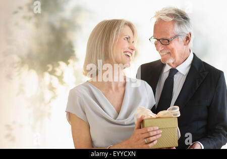 Smiling older Caucasian man giving wife a gift Stock Photo