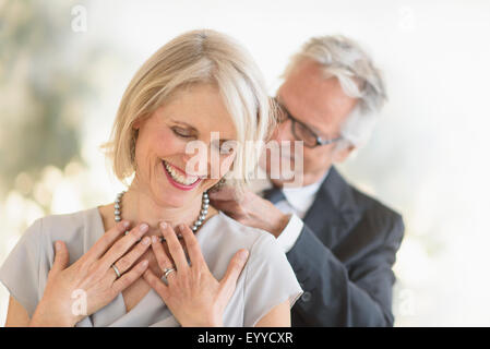 Smiling older Caucasian man giving wife a necklace Stock Photo