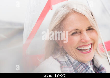 Older Caucasian woman standing under umbrella Stock Photo