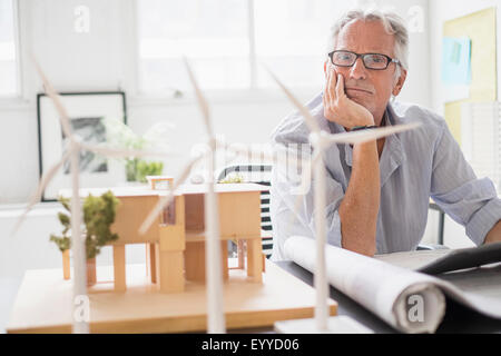 Older Caucasian architect examining scale model in office Stock Photo