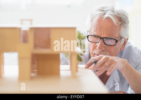 Older Caucasian architect building scale model in office Stock Photo