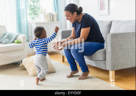 Mixed race mother playing with baby son in living room Stock Photo
