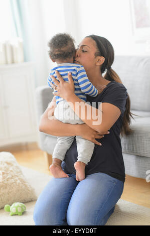 Mixed race mother kissing baby son in living room