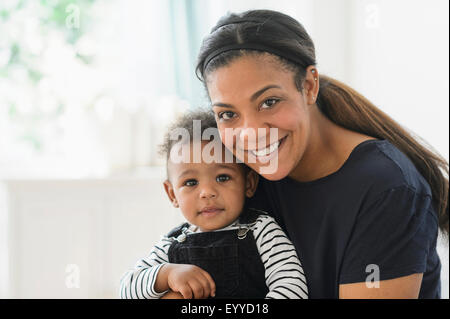Mixed race mother holding baby son in living room Stock Photo