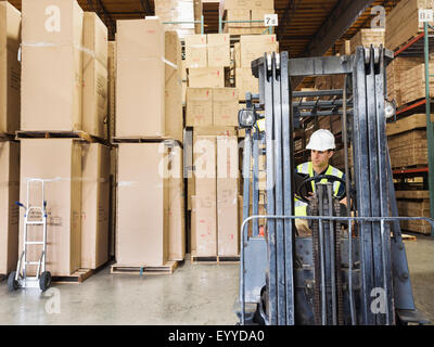 Caucasian worker driving forklift in warehouse Stock Photo