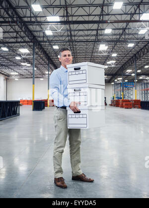 Caucasian businessman carrying boxes in empty warehouse Stock Photo