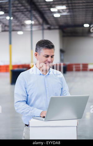 Caucasian businessman using laptop in empty warehouse Stock Photo