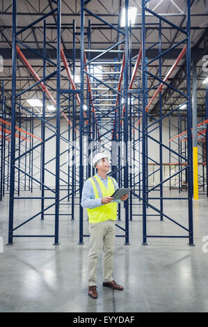 Caucasian worker using digital tablet in empty warehouse Stock Photo