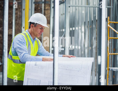 Caucasian architect reading blueprints at construction site Stock Photo