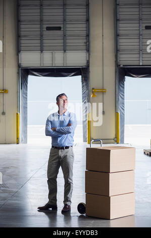 Caucasian businessman standing near cardboard boxes in warehouse Stock Photo