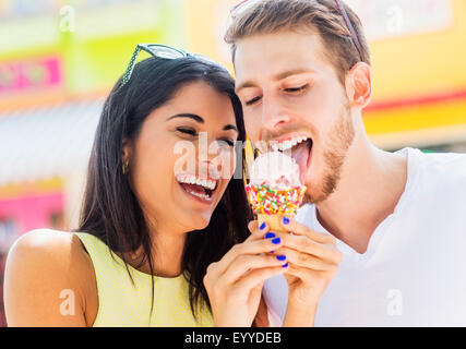Hispanic couple sharing ice cream cone outdoors Stock Photo