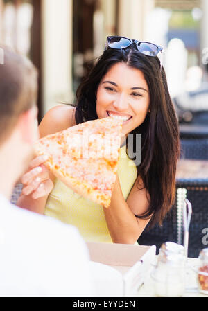 Hispanic couple eating pizza at cafe Stock Photo