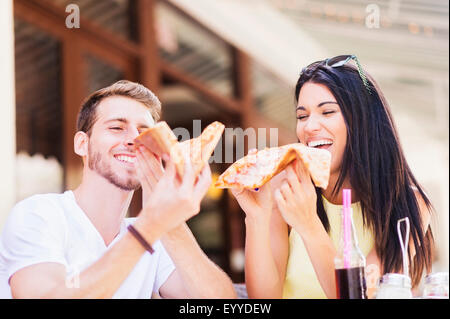 Hispanic couple eating pizza at cafe Stock Photo
