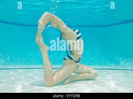 Underwater view of Caucasian woman practicing yoga in swimming pool Stock Photo