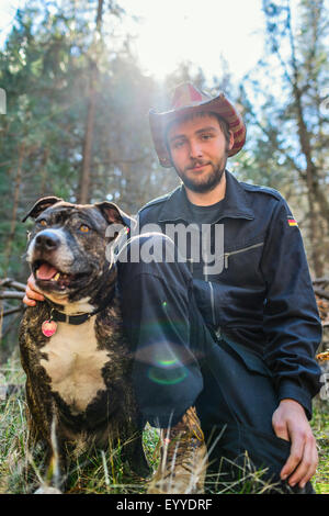 Caucasian man sitting with dog in field Stock Photo