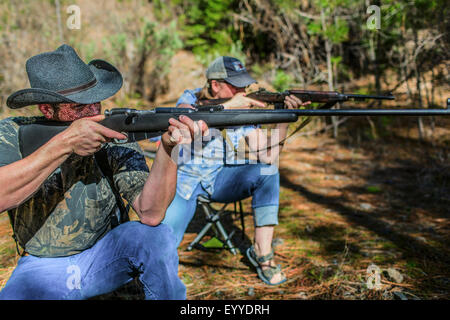 Caucasian hunters aiming guns in forest Stock Photo