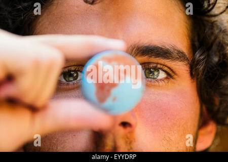 Close up of Hispanic man holding miniature globe Stock Photo