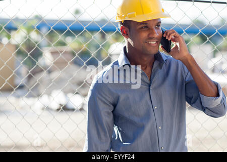 Black architect in hard hat talking on cell phone Stock Photo