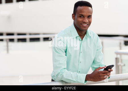 Black businessman using cell phone on balcony Stock Photo