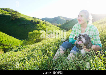 Older Caucasian woman walking dog on grassy hillside Stock Photo