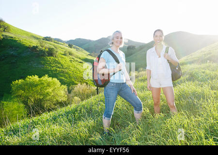 Caucasian mother and daughter smiling on grassy hillside