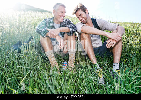 Caucasian father and son sitting on grassy hillside Stock Photo