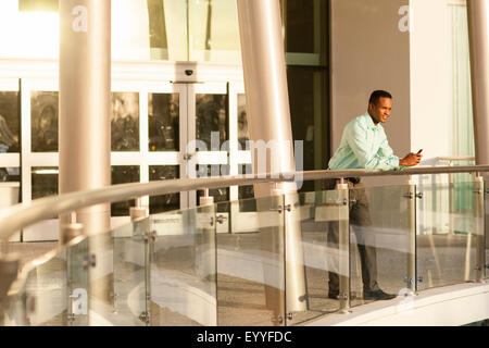 Black businessman using cell phone on railing Stock Photo